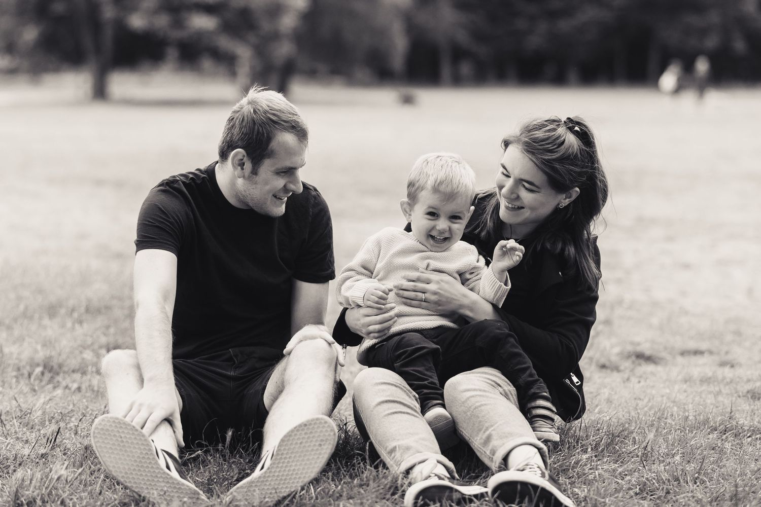 family playing whilst sitting on the grass, smiling