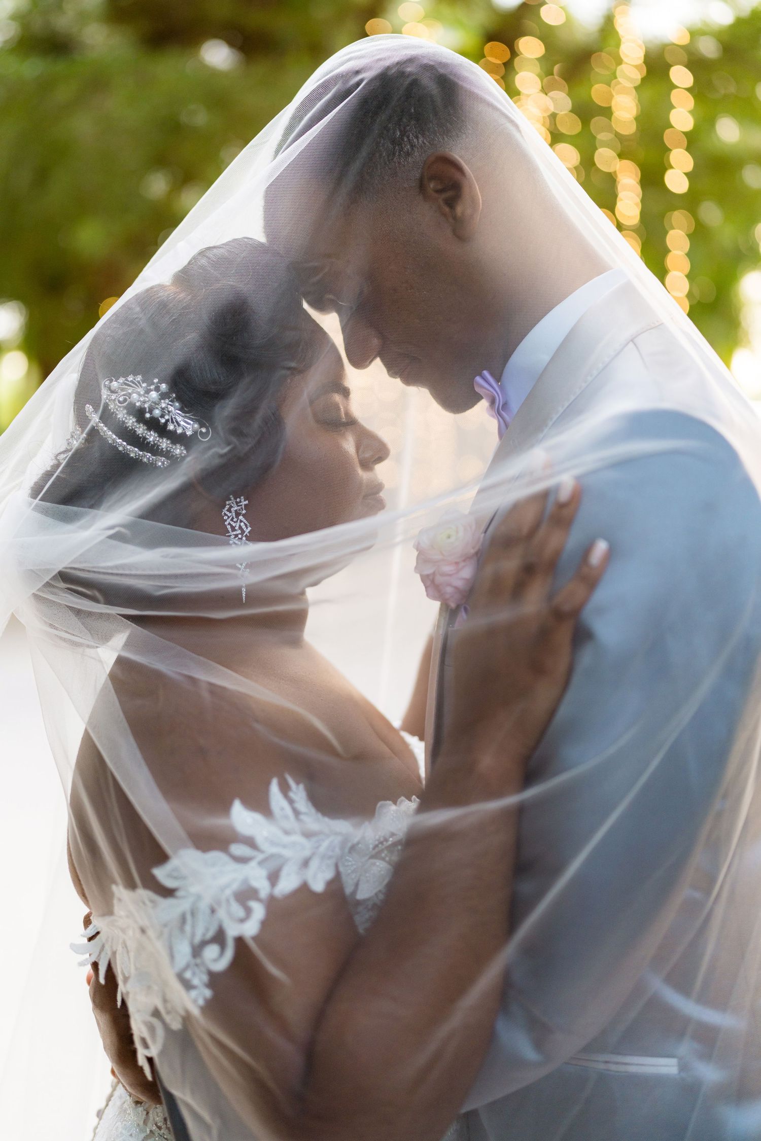 Intimate portrait of couple under sheer veil with golden sunset lighting.