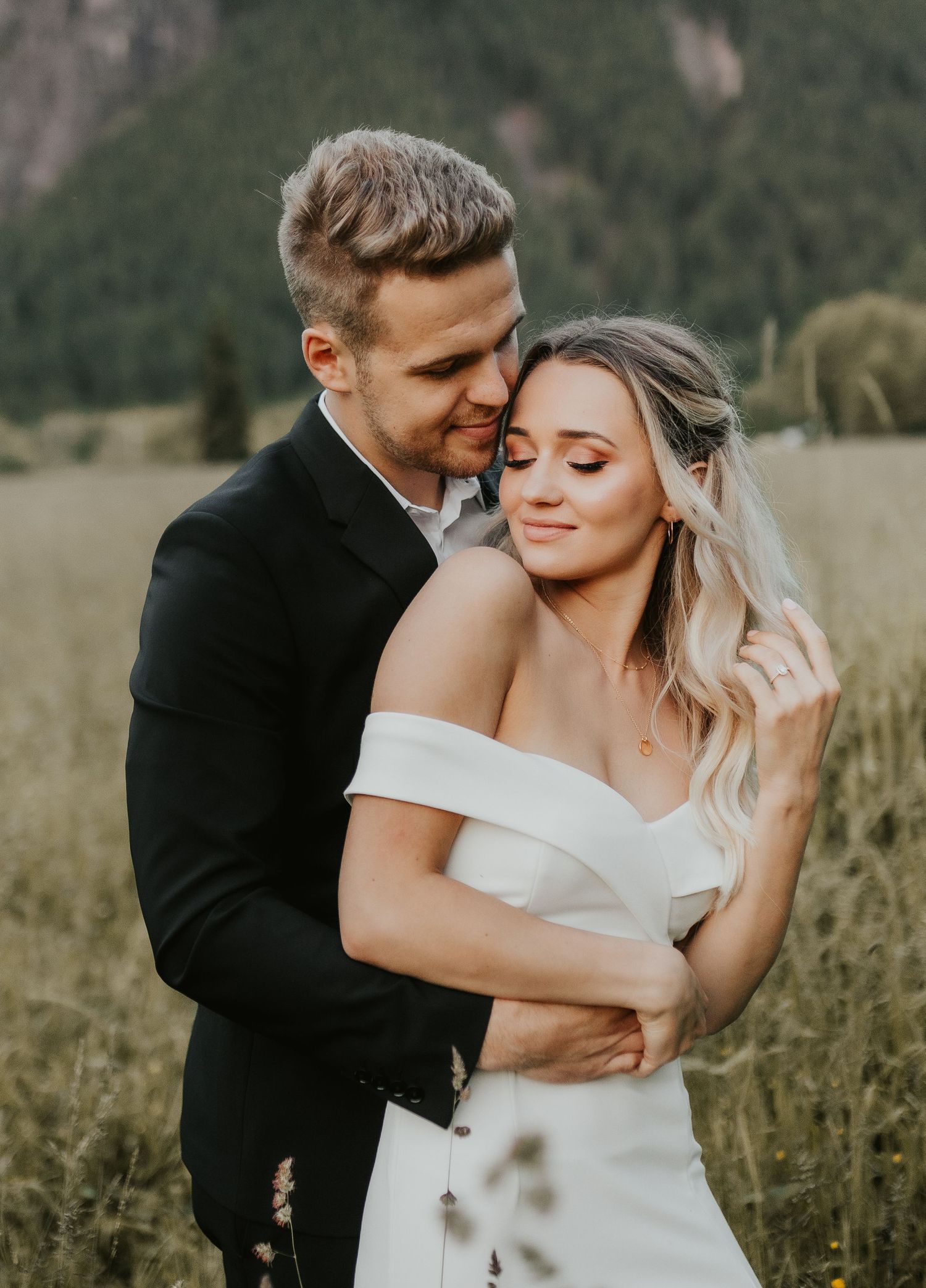 A romantic portrait of newlyweds embracing in a scenic mountain meadow.