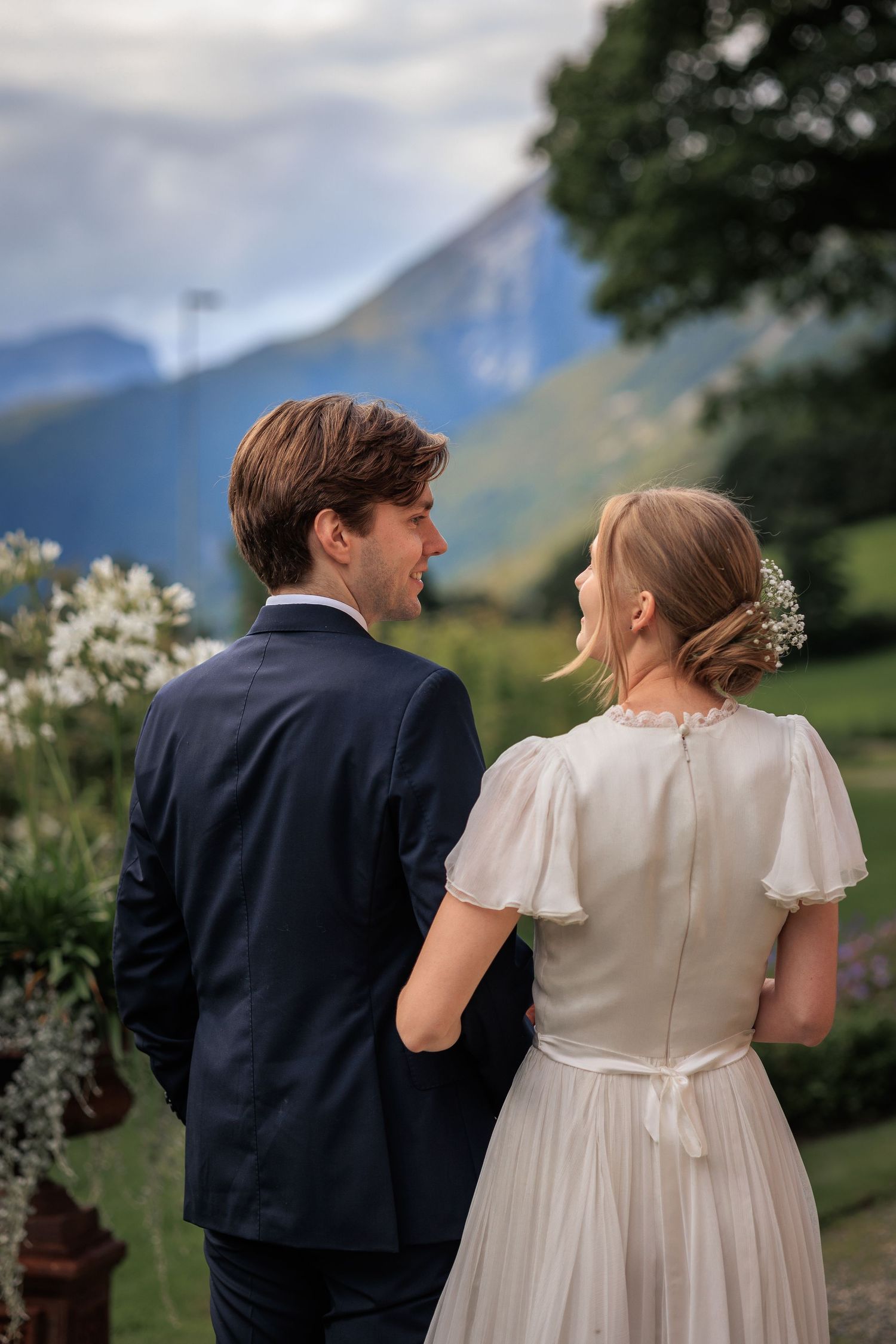 A wedding couple overlooking mountain views with the bride in a flutter sleeve dress.