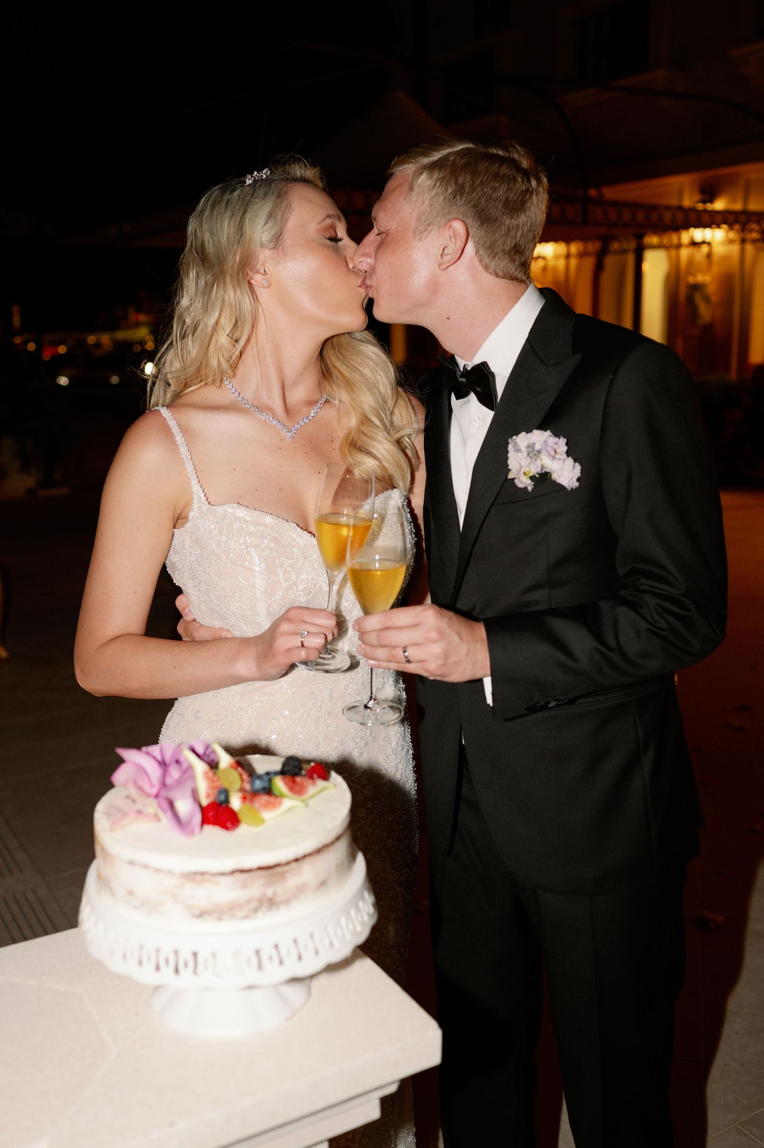 Romantic kiss between newlyweds during cake cutting ceremony.