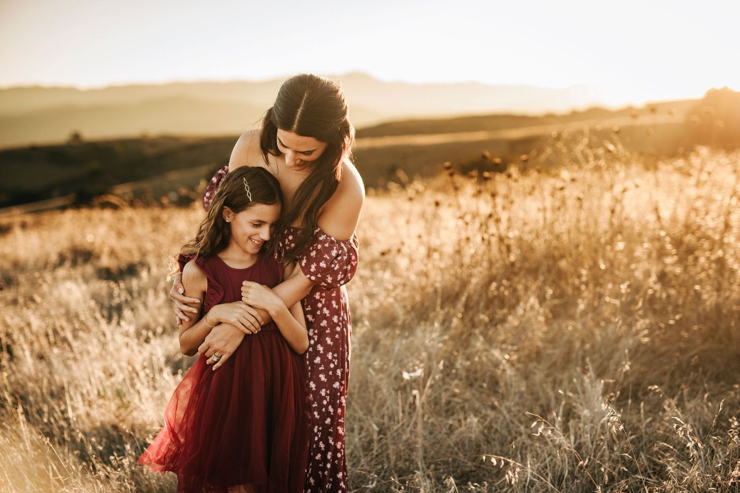 mom holding daugher in golden grasses