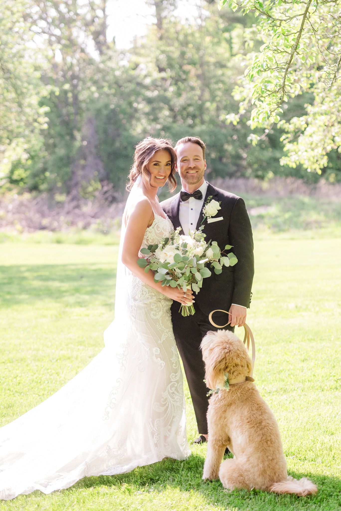 Couple looking at the camera while their Labrador gazes at them lovingly.
