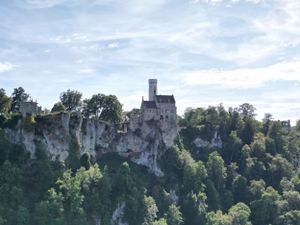A panoramic view of historic buildings perched atop limestone cliffs along the Dordogne River in France.