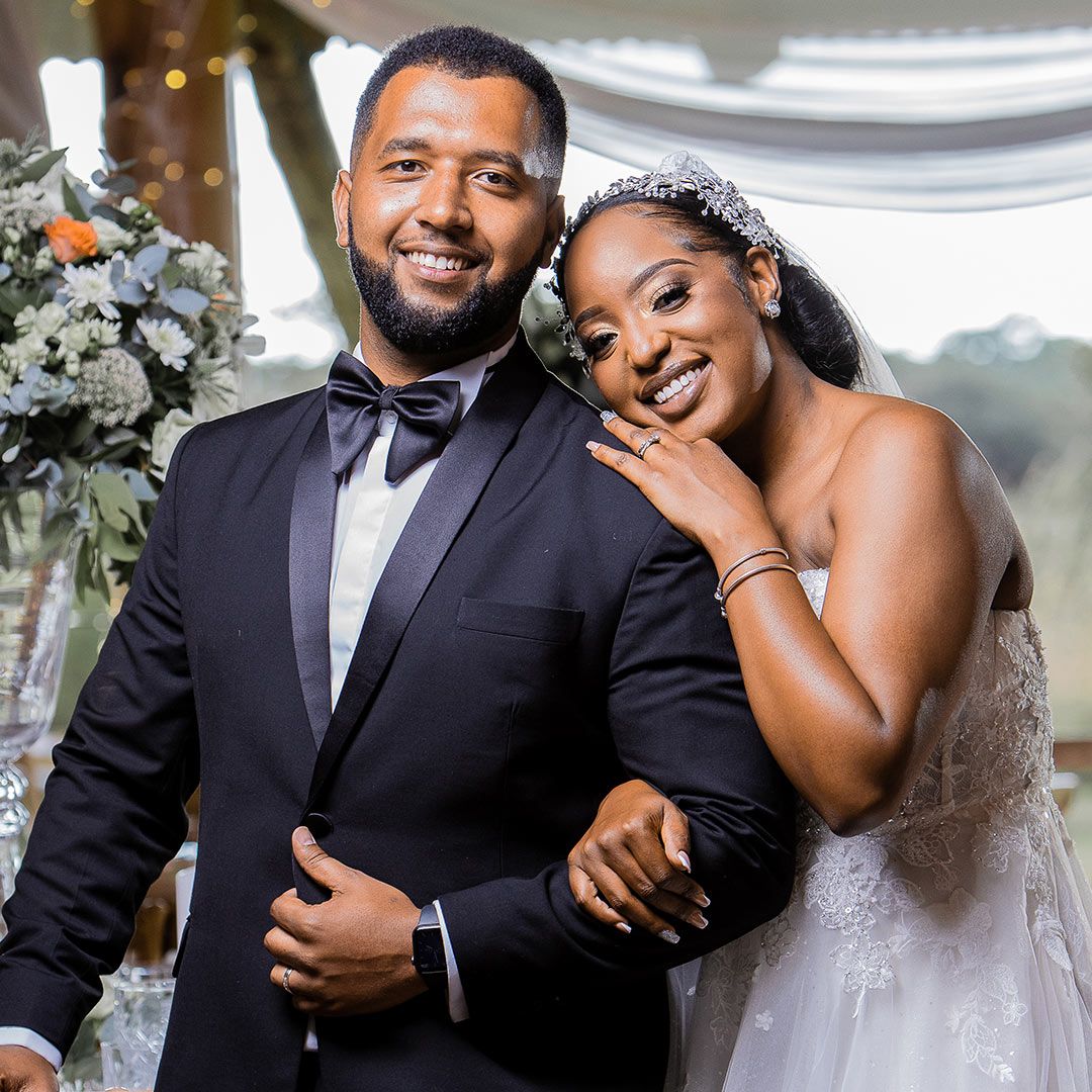 Wedding couple shares a joyful moment together, with bride in white dress and groom in classic black tuxedo.