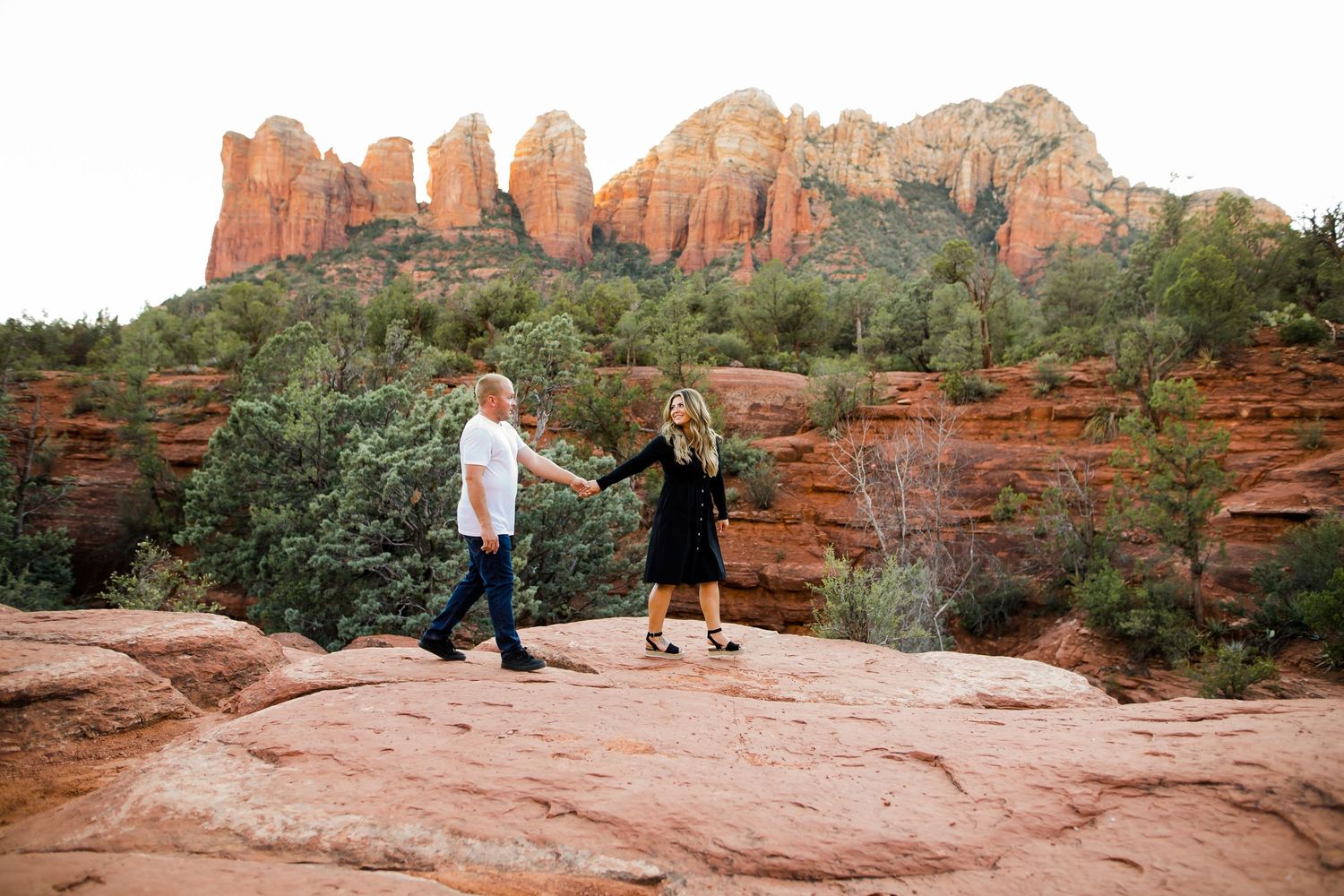 Stunning Sedona sunset view for this engagement session with a couple holding hands and walking along the mountains.