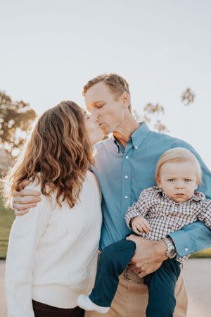 A tender family moment captured outdoors in warm sunlight.
