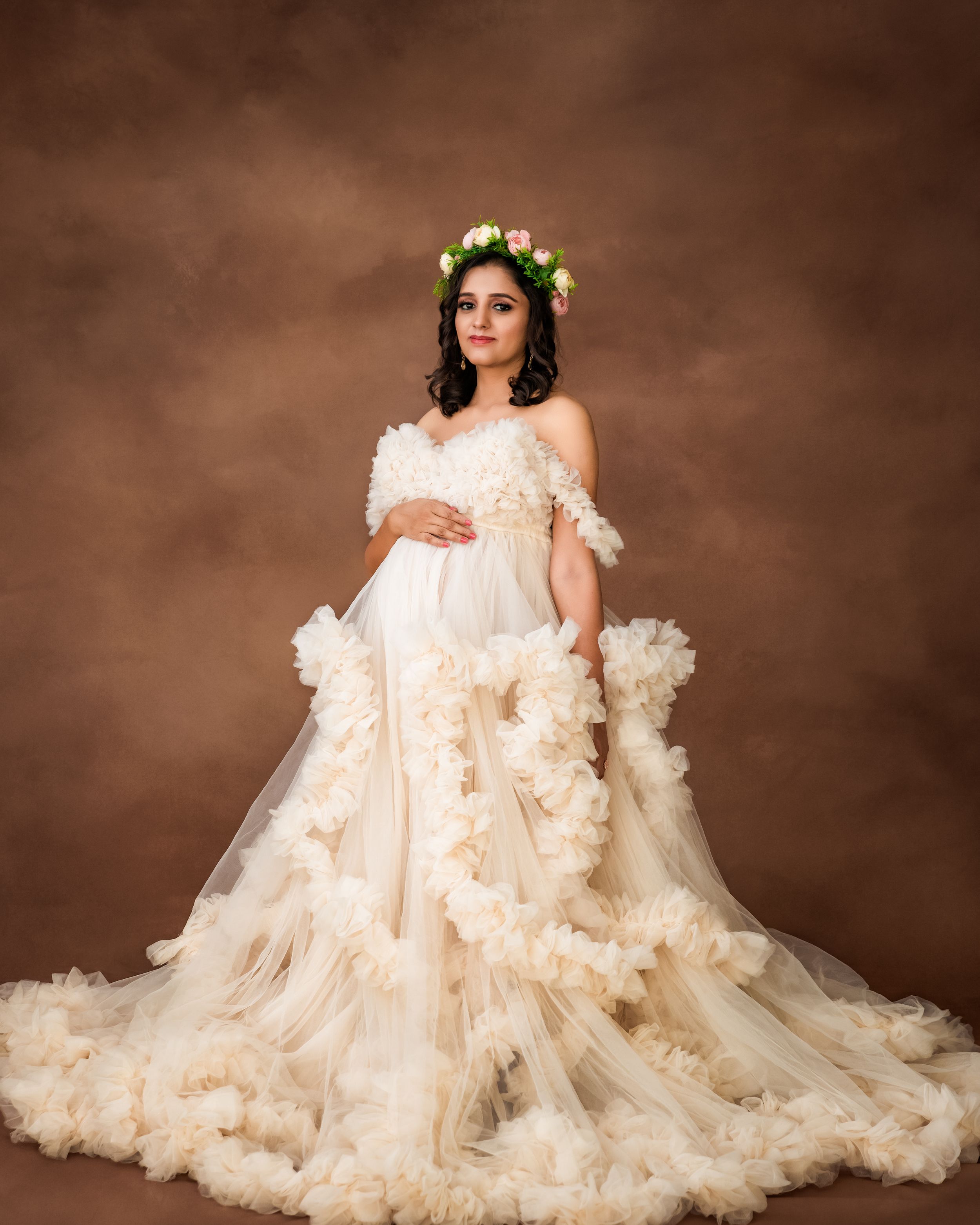 Ethereal maternity photo featuring an elaborate cream-colored tulle gown with cascading ruffles.