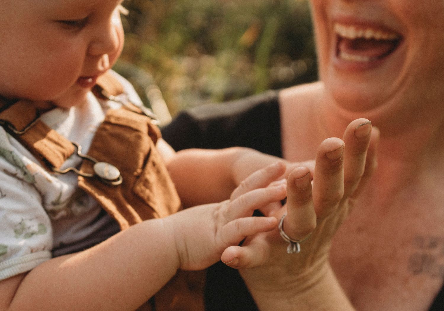 A close-up tender moment of hands touching during outdoor family time.