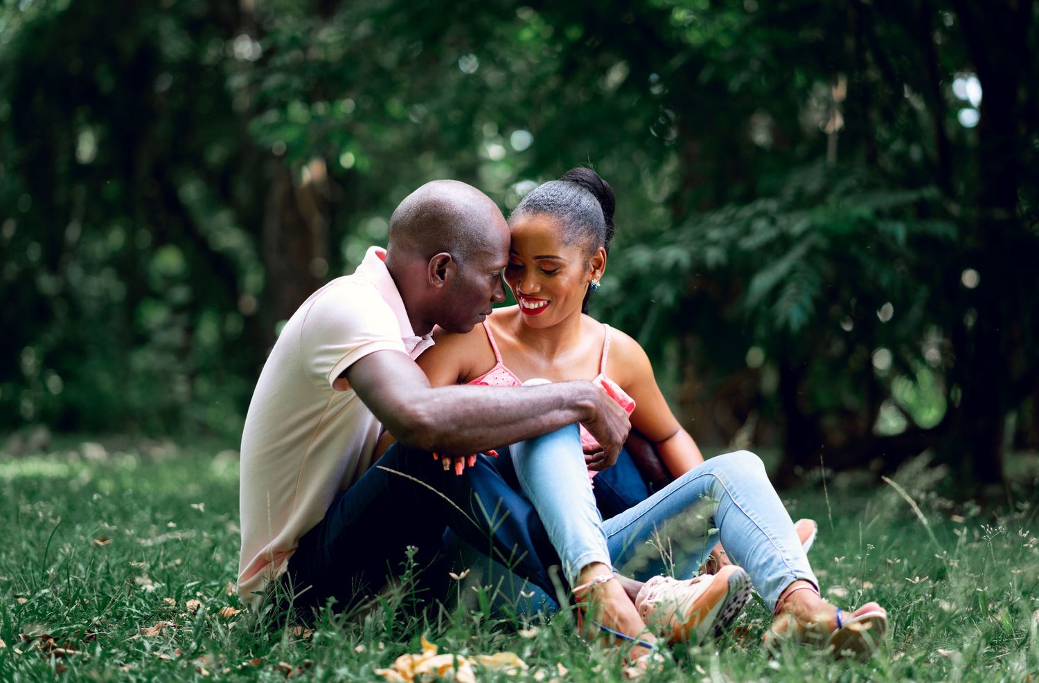 An intimate moment between parent and child sitting together on grass in a park.