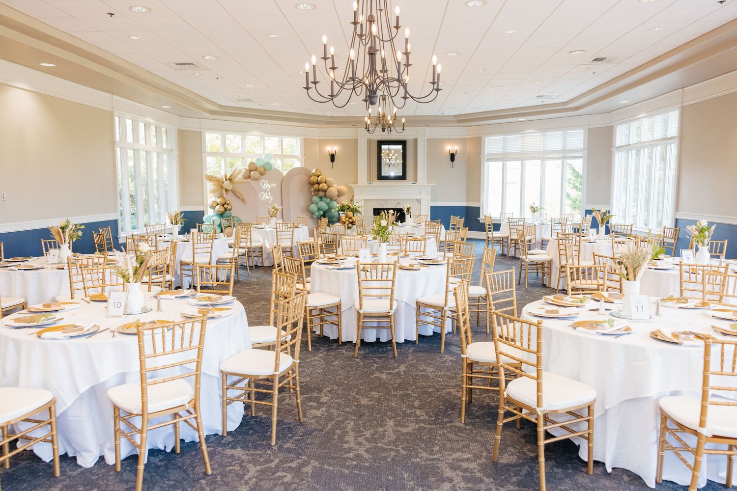 Elegant wedding reception venue with crystal chandelier and gold chiavari chairs.