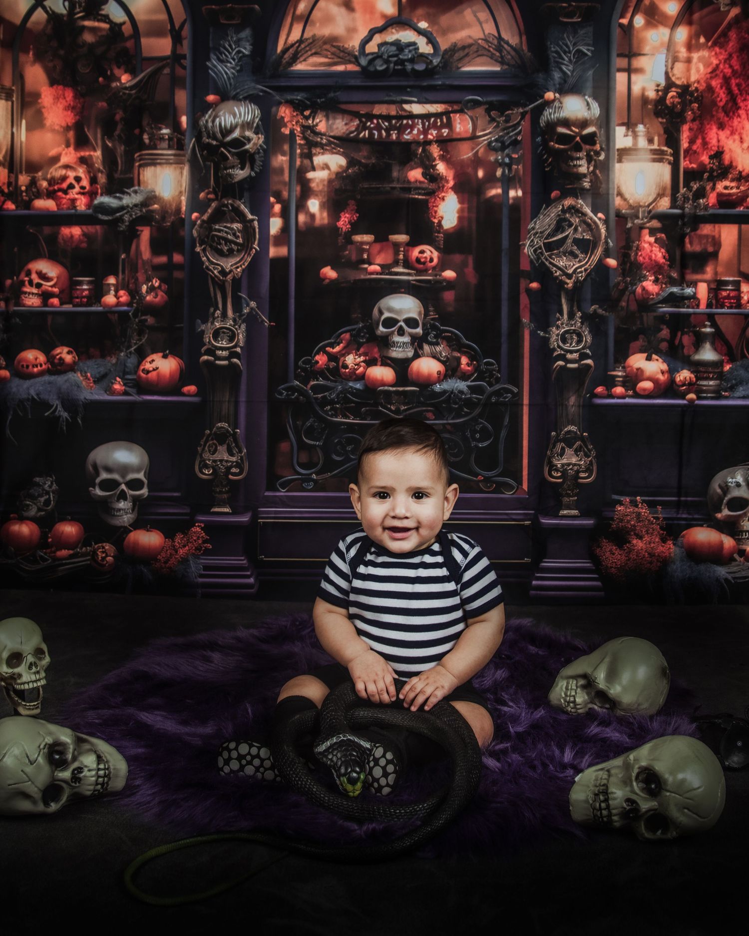 Spooky Halloween photo setup with skulls, pumpkins and gothic decor in dark purple and red tones.
