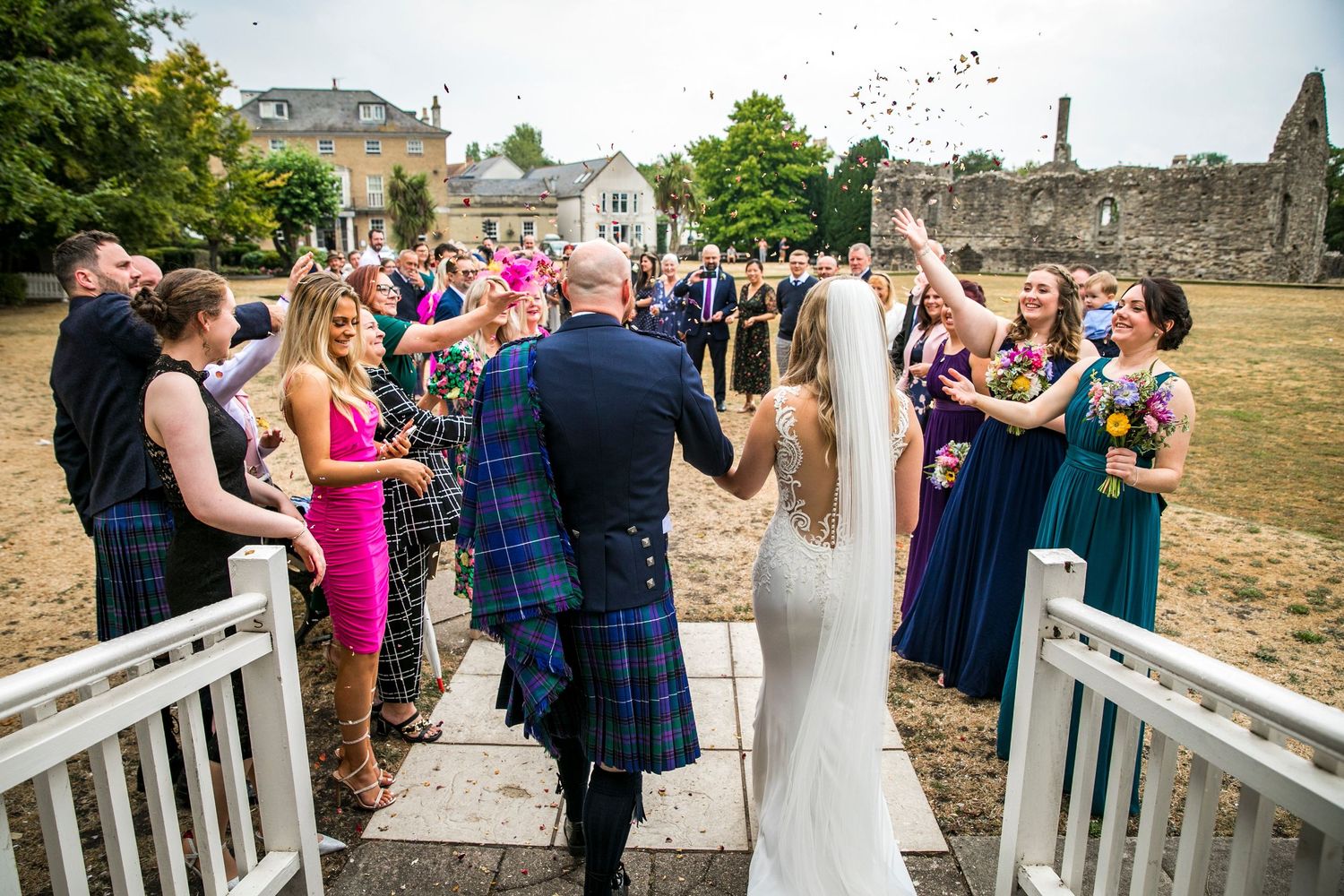 Wedding party posing on a white bridge with guests in the background.