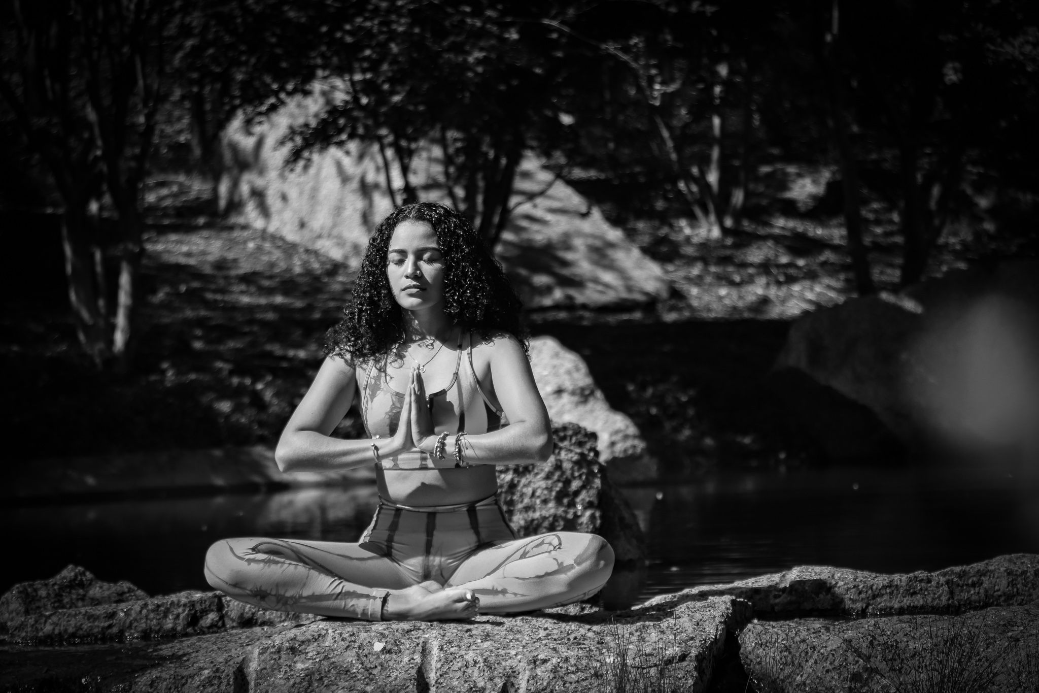Person meditating in lotus position outdoors in black and white photography.