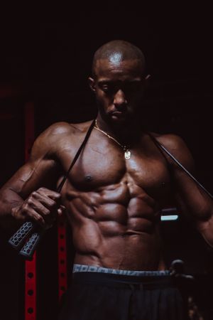 Athletic physique highlighted in dramatic lighting during intense workout session.