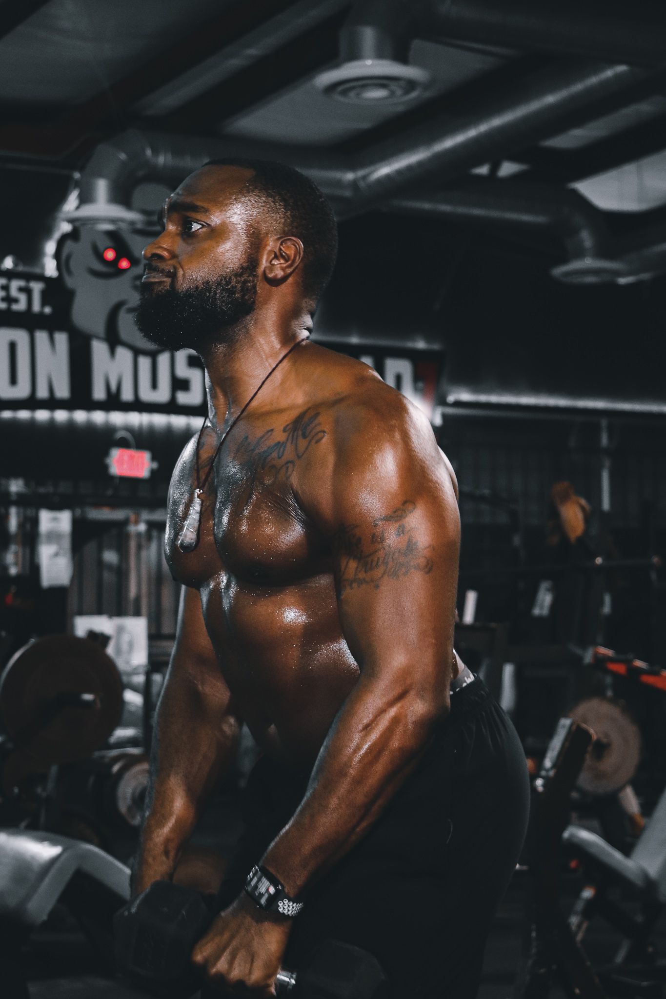 Athletic figure performing strength training exercises in dimly lit gym setting.