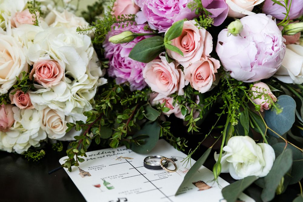 Wedding rings and bouquets of pink and white roses displayed with marriage certificate.
