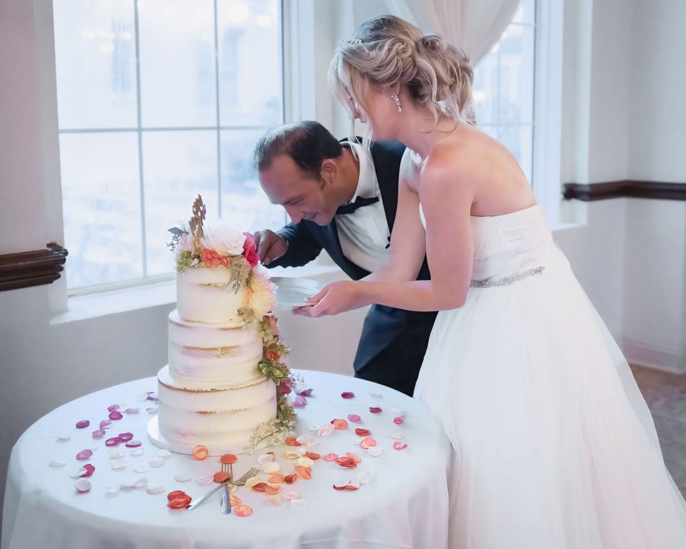A couple cutting their floral-decorated wedding cake together at their reception.