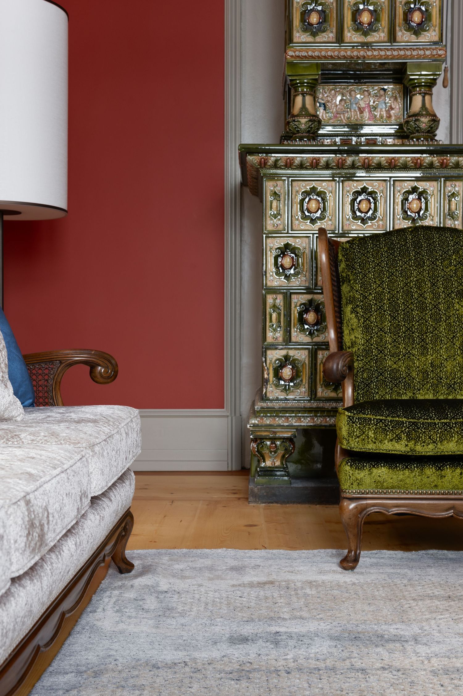 A traditional heating oven made in green ceramic tiles with a green chair in front