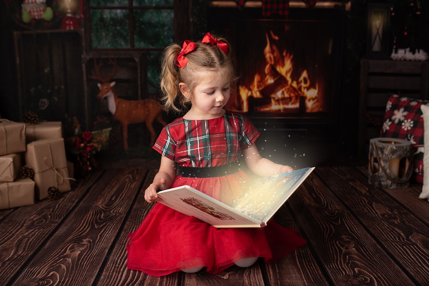 Young child in red dress reading magical glowing book by fireplace with Christmas decorations.