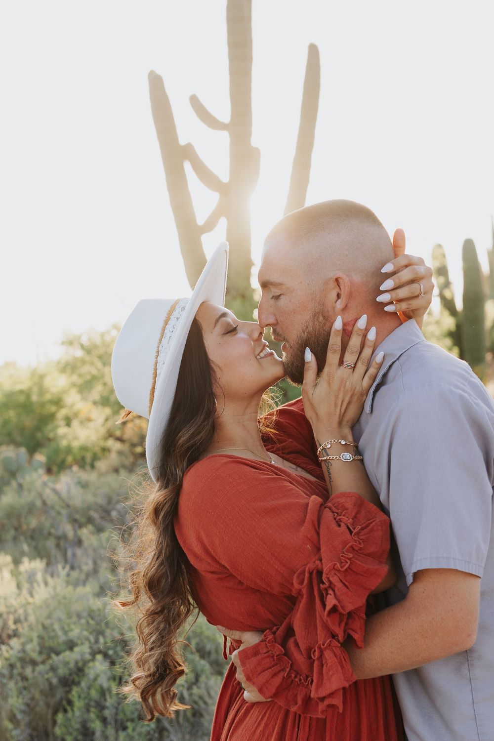 Romantic couple in desert setting sharing an intimate moment at sunset.