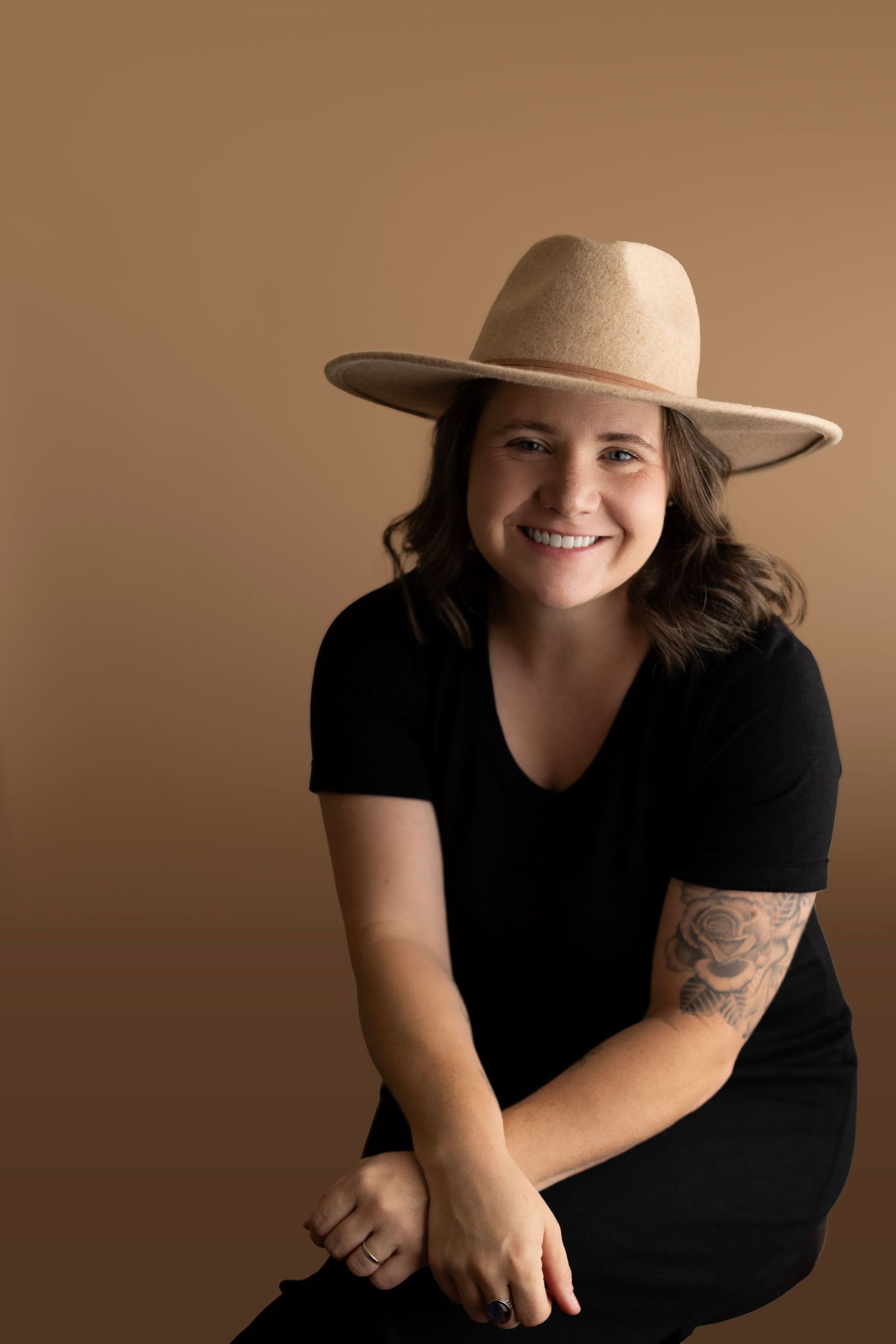 Woman with black dress and brown hat smiling at the camera.