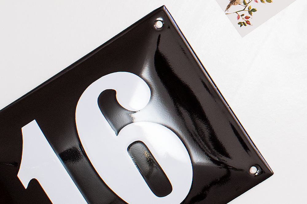 Black and white number 16 sign mounted on glossy surface.