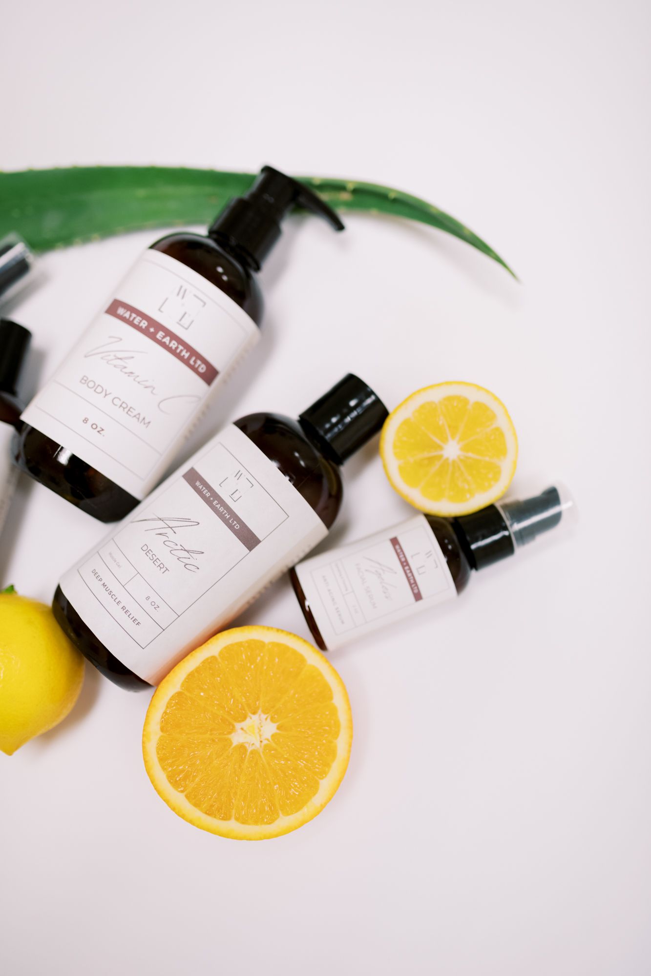 Skincare products with citrus slices and green leaf on white background.