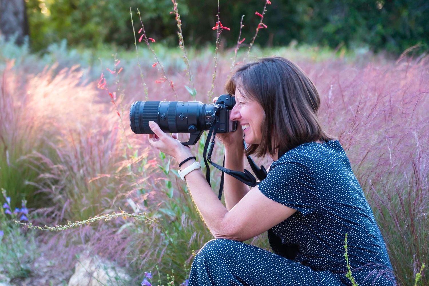 Photographer with telephoto lens captures images in field of pink ornamental grasses.