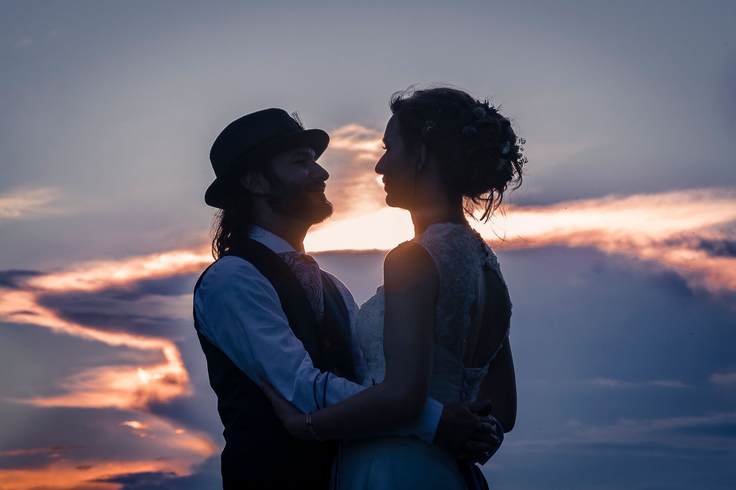 Bride and groom kiss at sunset during their wedding ceremony