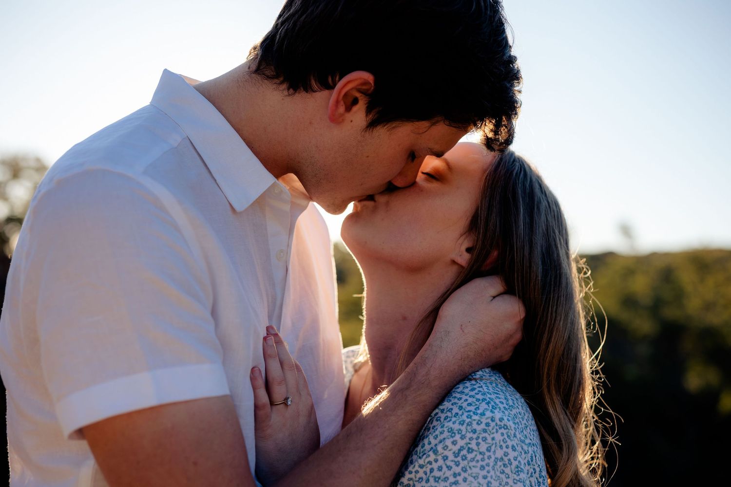 Romantic sunset embrace between couple in white summer attire.