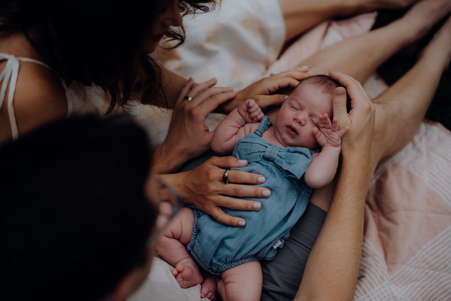A tender moment of parents comforting their baby on a bed.