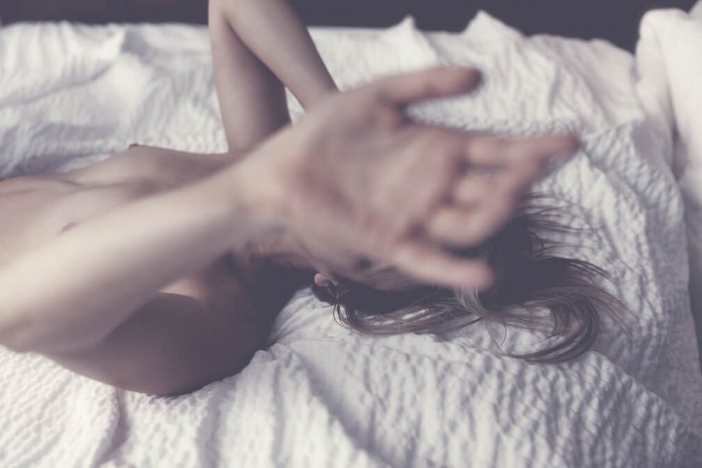 Soft focus intimate portrait on white bedding with artistic blur effect.