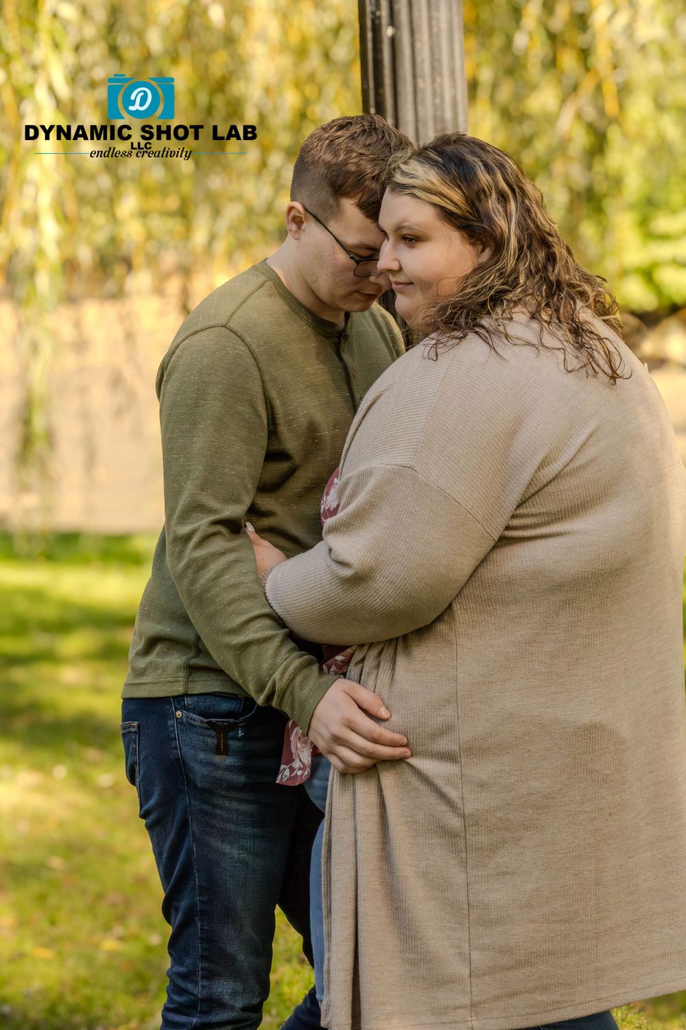 Intimate couple moment captured outdoors with soft natural lighting and greenery background.