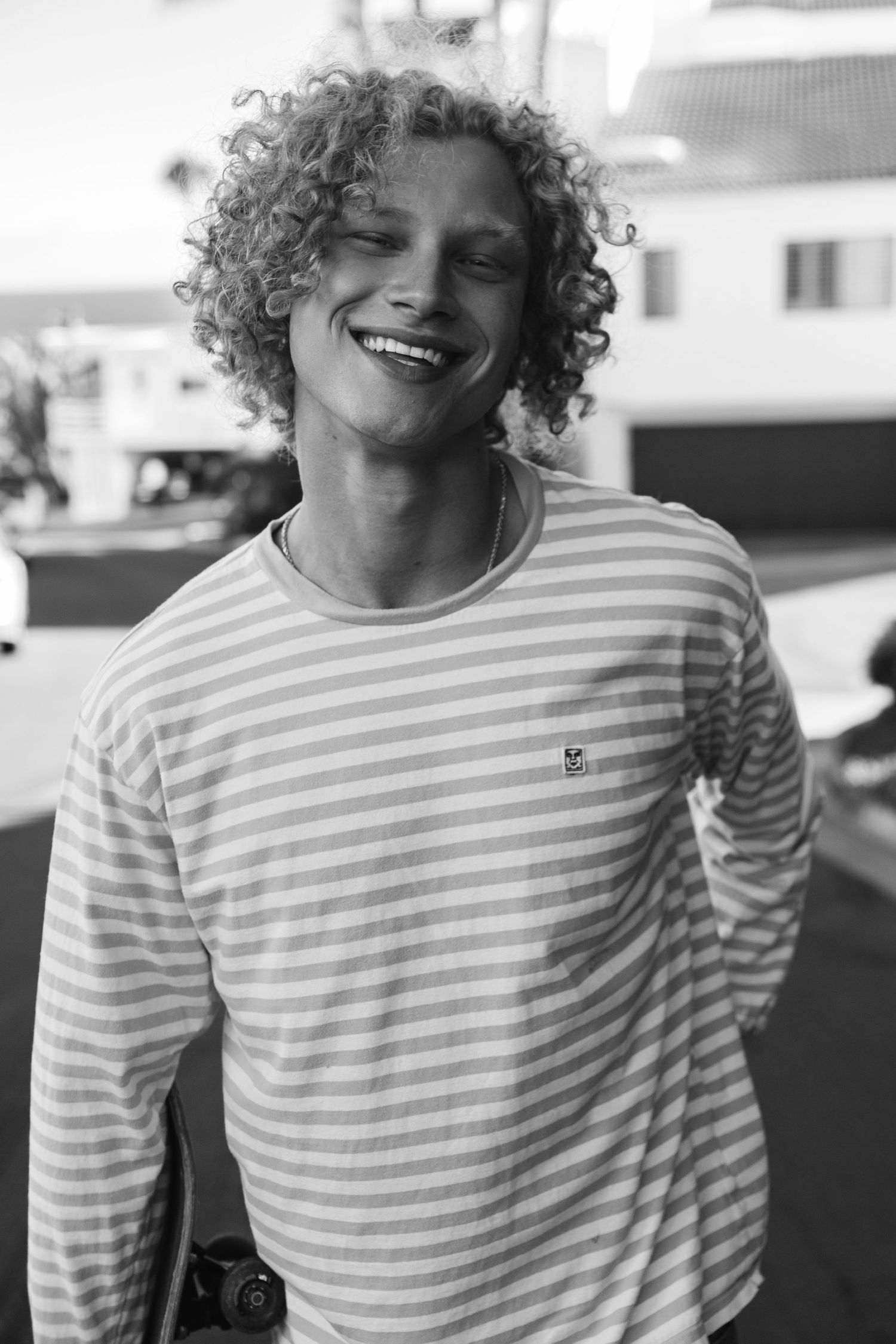 Curly blonde male model smiling in black and white portrait, San Clemente beach fashion editorial