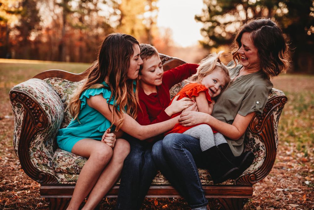family of 4 embracing on a vintage couch