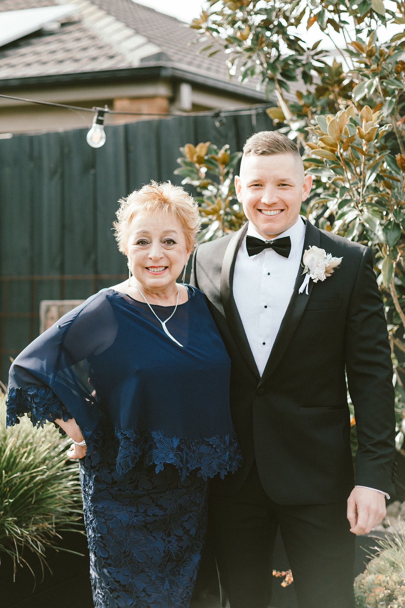 A heartwarming formal portrait of two people in elegant evening wear standing in a garden.