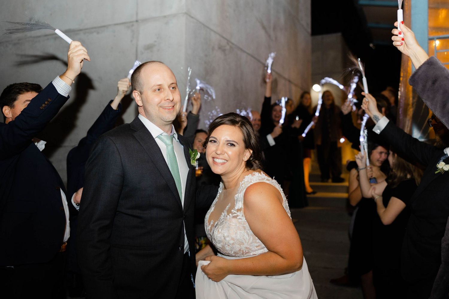 Wedding celebration with guests waving sparklers as newlyweds share a joyful moment.