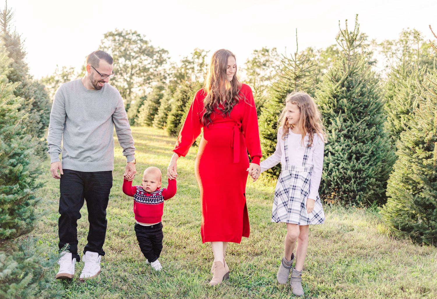 Family of 4 walking in a Hudson Valley, NY Christmas Tree farm wearing Gray, red and black and white plaid