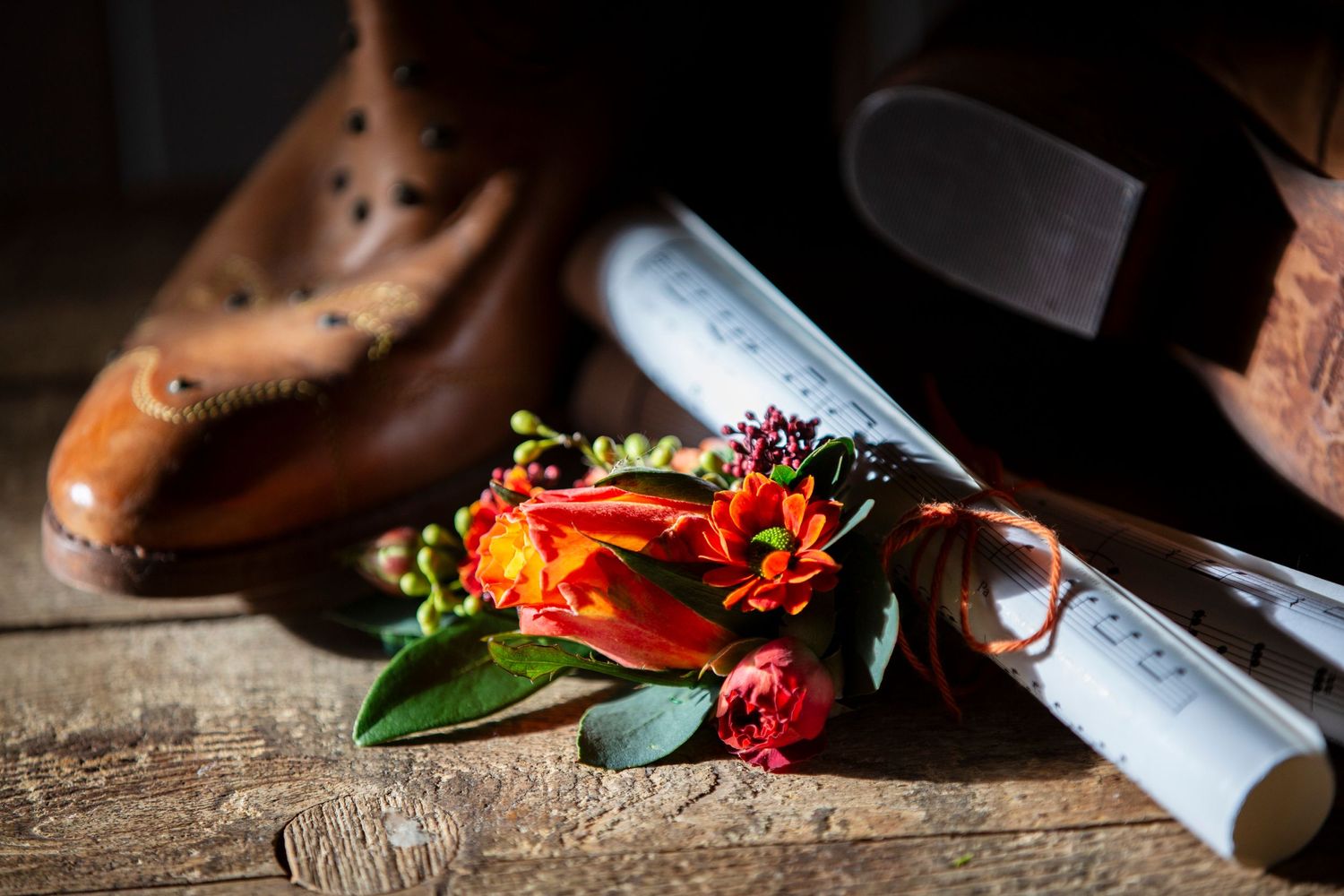 Wedding details featuring an elegant brown leather shoe with vibrant orange and red floral accents.