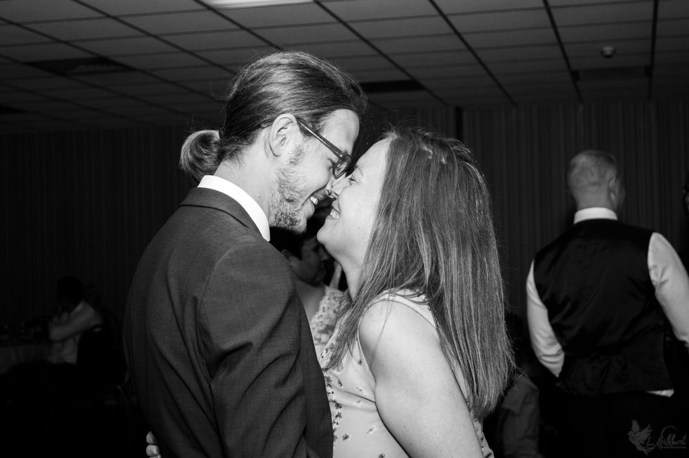 Black and white candid photo of romantic couple sharing an intimate moment at a party.