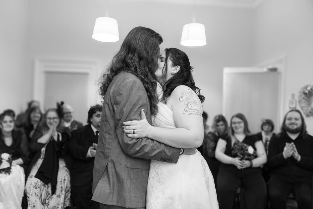 Black and white wedding photo of couple dancing while guests watch and applaud.
