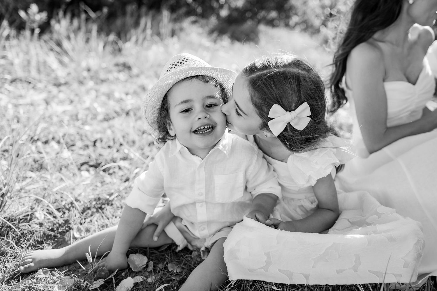 Two children in white outfits sitting together outdoors in a black and white photo.