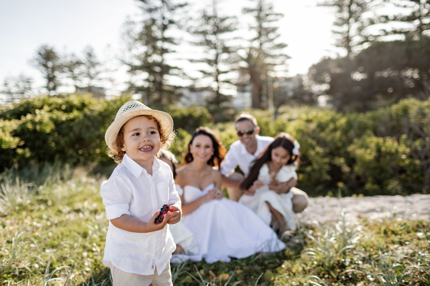 A casual outdoor family gathering in white attire among pine trees.