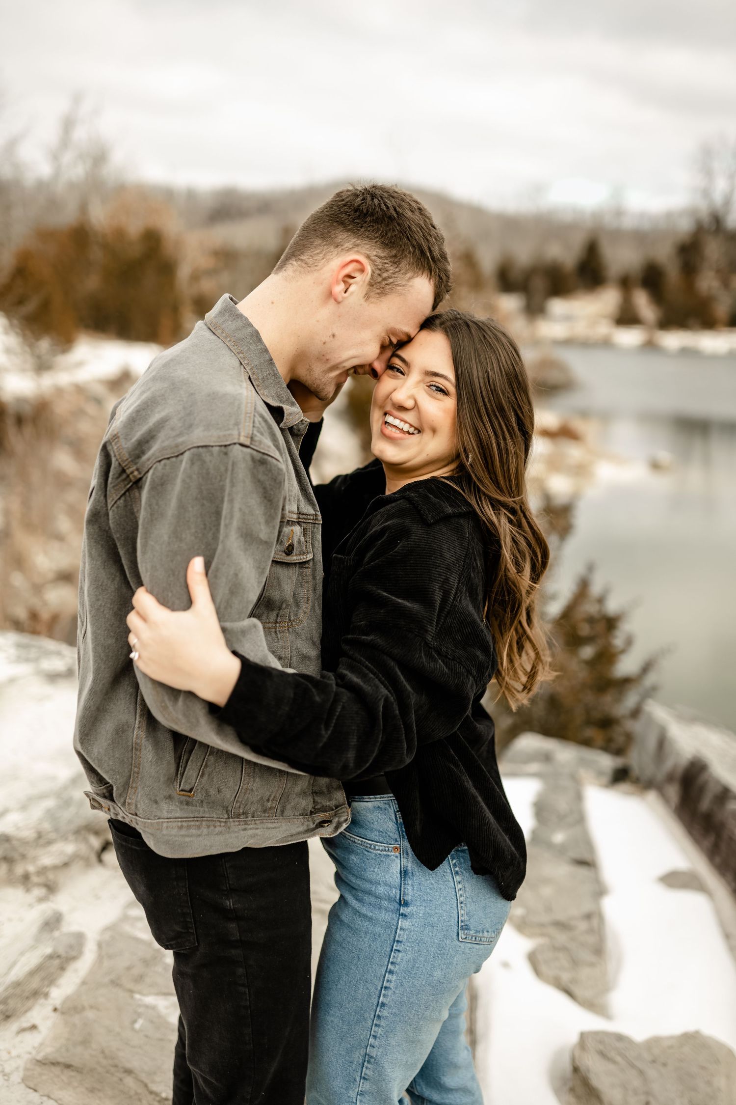 A couple shares tender moments during their winter photoshoot by a snow-covered lake.
