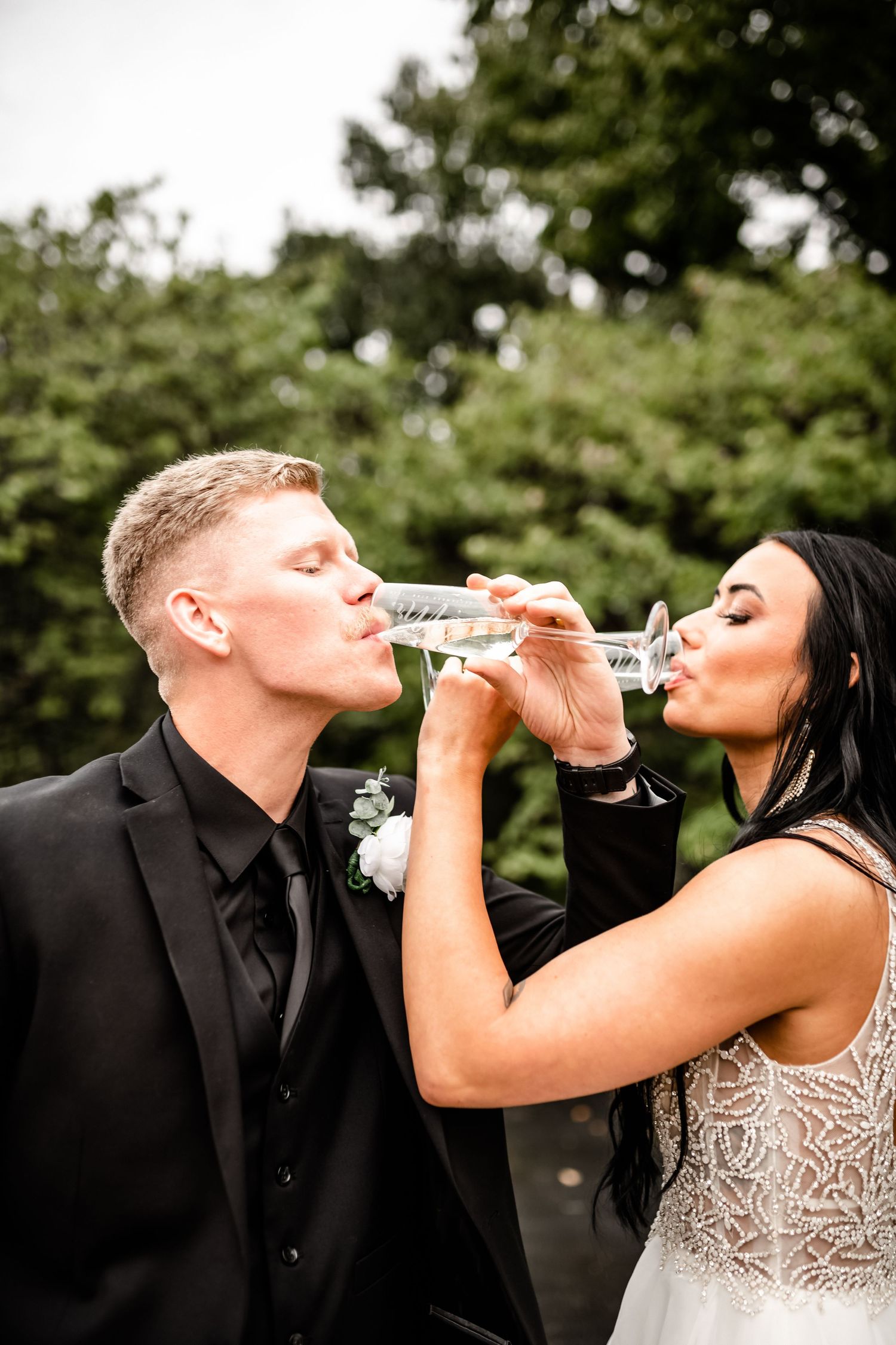 A couple shares champagne during their celebration outdoors.