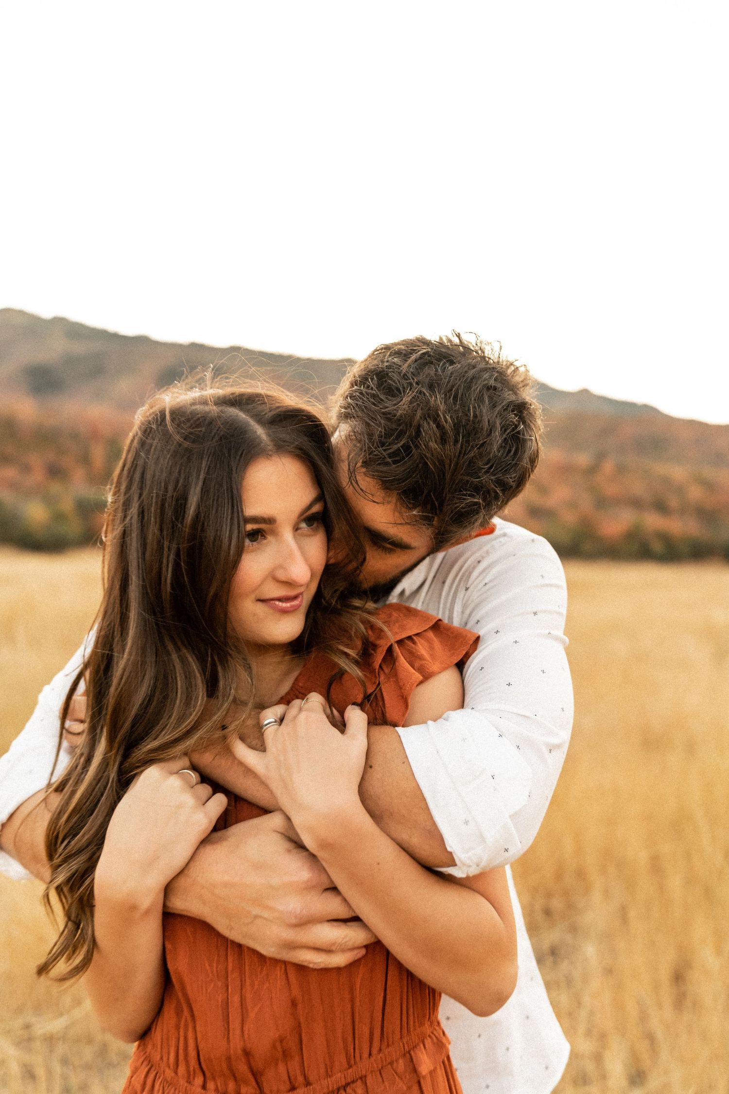Intimate couple portraits in a golden field during sunset showing tender moments.