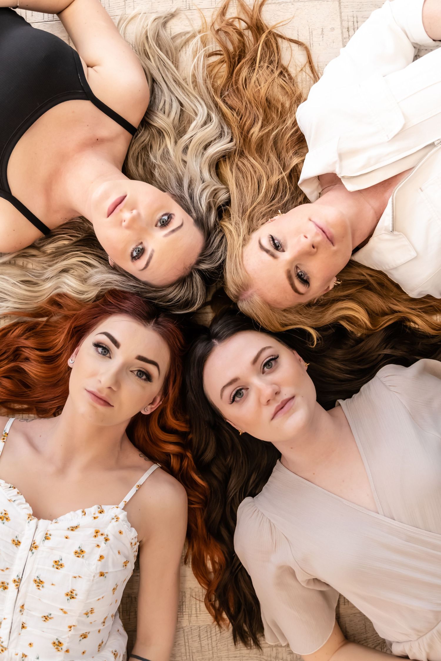 Group portrait with flowing hair arranged in circle formation against white background.