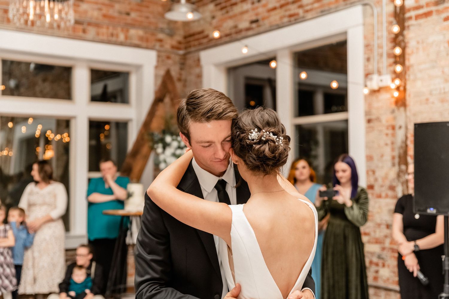 Wedding reception in rustic brick venue with string lights and elegant decor.