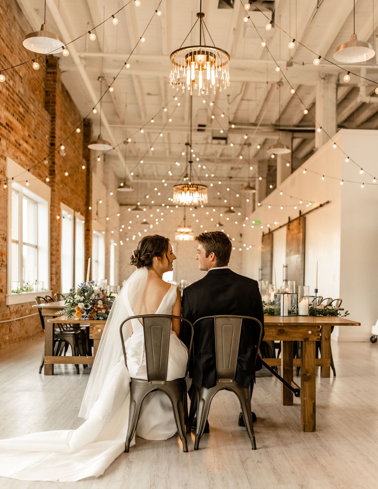 Elegant wedding venue features exposed brick walls, string lights and white modern decor.